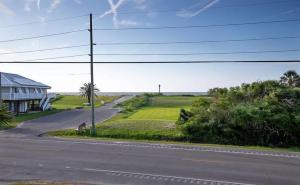 an empty road next to a house and a field at C'est Bon Across from UTV Entry Point! Sleeps 13! in Grand Isle +57 photos