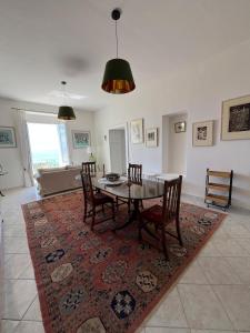 a dining room with a table and chairs on a rug at Casa di Candida in Amantea
