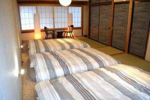 two beds in a room with a table and windows at 飛騨棲家 花里 憩 Hidasumika Hanasato Ikoi in Takayama