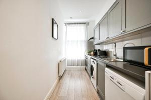 una cucina con mobili bianchi e pavimento in legno di Superb 1bed Ealing Apartment- Steps to Tube & City Attractions a Ealing Altre 8 foto