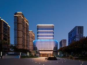 a large glass building in a city with tall buildings at Atour Hotel Yintai Department Store at Wenzhou South Station in Wenzhou