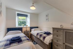 a bedroom with two beds and a dresser and a window at Pottery Cottage in Glanton
