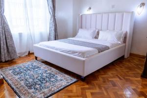 a bedroom with a white bed and a rug at Cozy Highland Private Bungalow in Eldoret in Eldoret