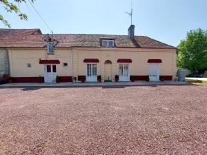 Un edificio antiguo con puertas blancas y ventanas rojas. en Le clos des oiseaux, en Maisnières