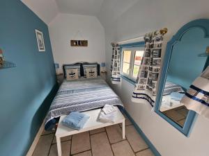 Un dormitorio pequeño con una cama y un espejo. en Le clos des oiseaux, en Maisnières