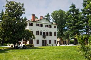 an old white house with a car parked in the yard at Villa Zane in Treviso