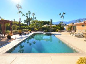 a swimming pool in a yard with palm trees at Casa de Cantera in Palm Springs