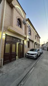 サマルカンドにあるBRICK PALACEの建物の前に駐車された白い車