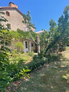 an old stone house with trees and bushes at Domaine du plô, Tarn in Trévien