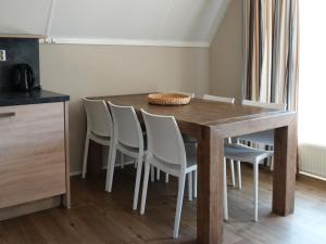 a dining room table with white chairs around it at Holiday Home Ruiten AA comfort by Interhome in Vlagtwedde +12 photos