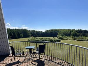 a balcony with a table and chairs and a field at Holiday Home Herlek - 450m from the sea by Interhome in Åkirkeby