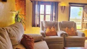a living room with two chairs with orange pillows at Cortijo El Potro in Órgiva