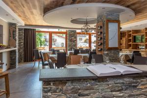ein Restaurant mit einer Steinbar mit Tischen und Stühlen in der Unterkunft Hotel K2 in Sauze dʼOulx