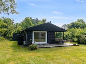 Una cabaña negra con terraza en un patio. en Holiday Home Josef - 1-4km from the sea by Interhome, en Rørvig