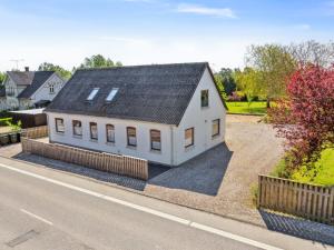 ein weißes Haus mit einem schwarzen Dach an der Seite einer Straße in der Unterkunft Holiday Home Teodora - 3km from the sea by Interhome in Tranekær