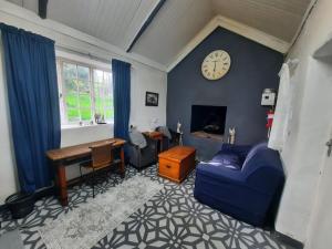 a living room with a blue couch and a clock on a wall at Stone Cottage in Grabouw