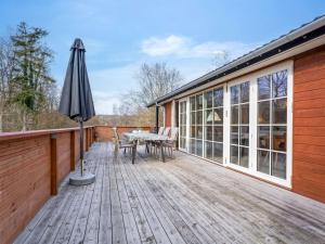 a wooden deck with a table and an umbrella at Holiday Home Preben - 50m from the sea by Interhome in Stege
