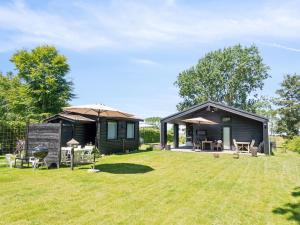 a log cabin with an umbrella in a yard at Holiday Home Huldrik - 100m from the sea by Interhome in Martofte