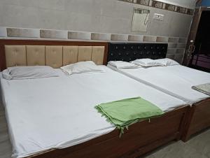 two beds with white sheets and a green blanket at saryu home stay in Ayodhya