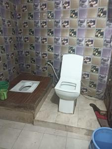 a bathroom with a toilet and a tile wall at saryu home stay in Ayodhya