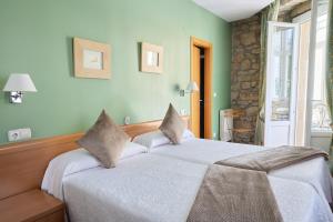 two beds in a bedroom with green walls at Pensión Nuevas Artes in Donostia-San Sebastián