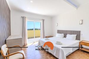 ein Schlafzimmer mit einem Bett und einem großen Fenster in der Unterkunft #336 Vila Sol by Home Holidays in Sesmarias