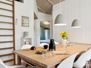 une salle à manger avec une table en bois et des chaises blanches dans l'établissement Holiday Home Amiira - 500m from the sea by Interhome, à Gilleleje