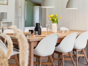 une salle à manger avec une table en bois et des chaises blanches dans l'établissement Holiday Home Amiira - 500m from the sea by Interhome, à Gilleleje