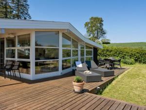 a wooden deck with chairs and tables on a house at Holiday Home Fokke - 450m from the sea by Interhome in Aabenraa