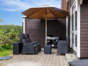 een patio met een parasol, stoelen en een grill bij Holiday Home Annrike - 175m to the inlet by Interhome in Jægerspris