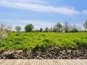 a grassy field with a wooden walkway and rocks at Holiday Home Sölvy - 300m from the sea by Interhome in Børkop
