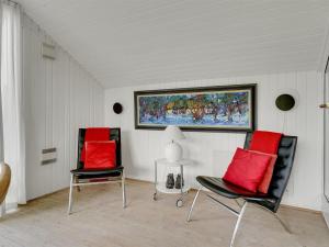 Dos sillas con cojines rojos en una habitación con un cuadro en Holiday Home Magnus - 250m to the fjord by Interhome, en Esbjerg