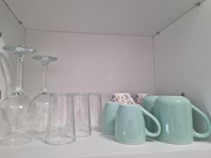 a row of cups and glasses on a shelf at Studio Nova - Minimalist and Elegant with Parking in Bucharest