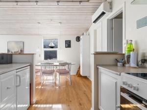 a kitchen with white cabinets and a table with chairs at Holiday Home Answald - 10m from the sea by Interhome in Nyborg