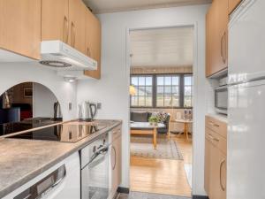 a kitchen with white appliances and a living room at Holiday Home Thorir - 500m from the sea by Interhome in Dannemare