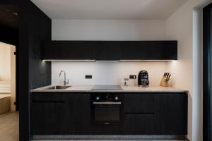 a kitchen with black cabinets and a sink at Hochegg Hideaway in Laives +16 photos