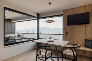 a dining room with a table and chairs and a large window at Hochegg Hideaway in Laives