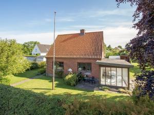 a red brick house with a conservatory on a lawn at Holiday Home Sakulf - 500m from the sea by Interhome in Sæby