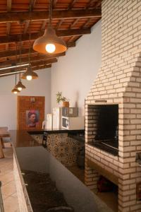 a living room with a brick fireplace with a television at Pousada Palmeira-Imperial in Pirenópolis