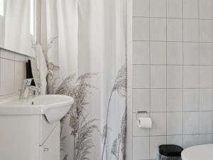 Un baño con cortina de ducha y lavabo. en Apartment Felicia - 200m from the sea by Interhome, en Neksø