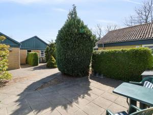 Un patio con un seto y una mesa y un árbol. en Apartment Felicia - 200m from the sea by Interhome, en Neksø