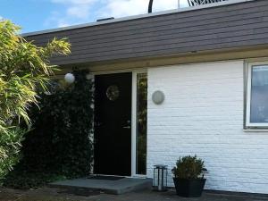 a white house with a black door and ivy at 4 star holiday home in Sölvesborg in Hällevik