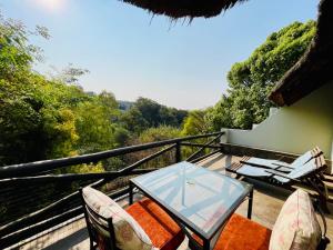 a patio with a glass table and chairs on a balcony at Pretoria Mansion Boutique Hotel Coral Tree in Pretoria