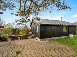 a black house with a fence and a patio at Holiday Home Lenya - 300m to the fjord by Interhome in Struer +17 photos