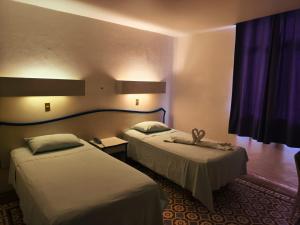 zwei Betten in einem Hotelzimmer mit lila Vorhängen in der Unterkunft HOTEL OLIDEN in Coatzacoalcos