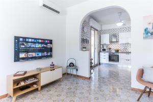 a kitchen with white cabinets and a tv on the wall at Verde Mare, appartamento in centro a Marina vicino alla spiaggia in Marina di Ragusa