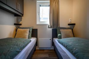 two beds in a small room with a window at Chalet NewPort 068 im Naturpark Schwalm-Nette in Brüggen
