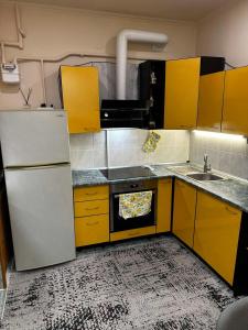 a kitchen with yellow cabinets and a white refrigerator at Чернівці Апартаменти in Chernivtsi
