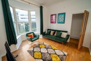 a living room with a green couch and a chair at Cosy 3-Bed Swansea Home near City & Bay in Swansea