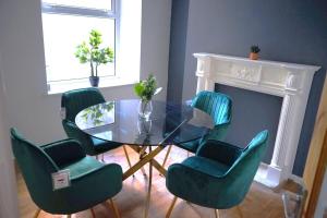 a dining room with a glass table and green chairs at Cosy 3-Bed Swansea Home near City & Bay in Swansea +27 photos